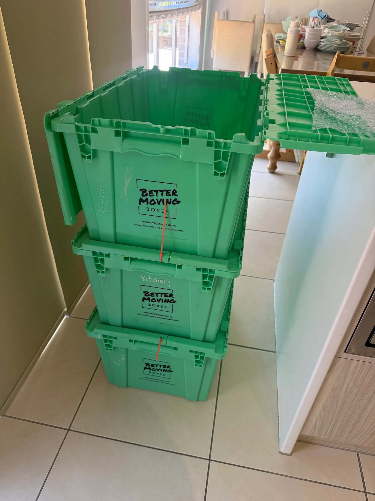 Stack of green Better Moving Boxes crates labelled 'Kitchen' in a Central Coast home